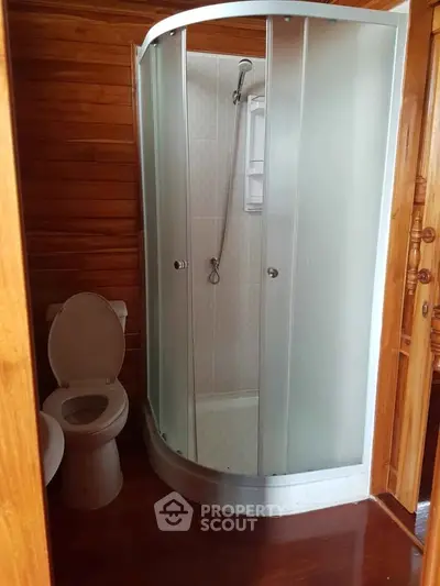 Cozy bathroom with modern shower and wooden accents, perfect for a rustic home.