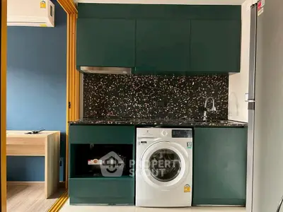 Modern kitchen with washing machine and sleek cabinetry in compact apartment.