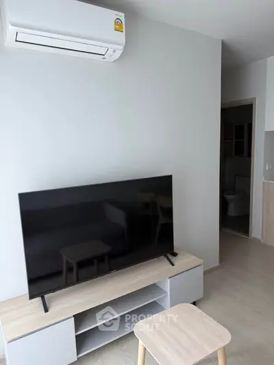 Modern living room with sleek TV and air conditioning in a stylish apartment.