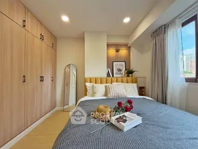 Cozy bedroom with modern decor, large wardrobe, and natural light from window.