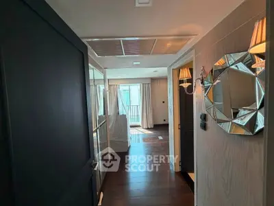 Elegant hallway leading to a bright living area with stylish decor and wooden flooring.