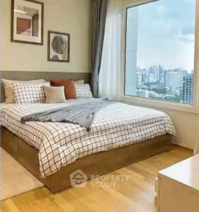 Modern bedroom with large window offering stunning city views and stylish decor.