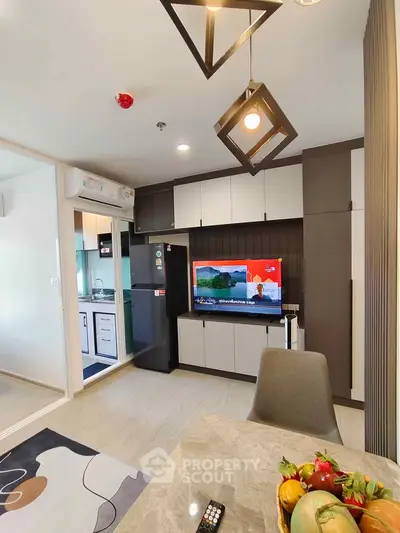 Modern living room with stylish decor and open kitchen layout, featuring sleek cabinets and contemporary lighting.