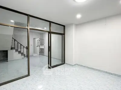 Spacious empty room with glass doors and staircase, ideal for customization.