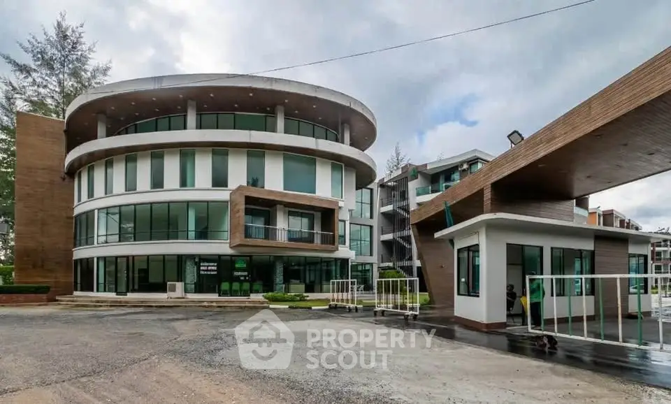 Modern circular building with glass facade and adjacent structures in a spacious outdoor setting.