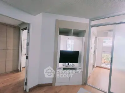 Modern apartment interior with TV and sliding glass doors leading to balcony