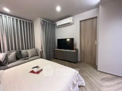 Modern bedroom with cozy bed, stylish sofa, and sleek TV setup in a contemporary apartment.