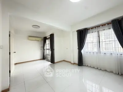Spacious bright living room with large windows and modern air conditioning unit.
