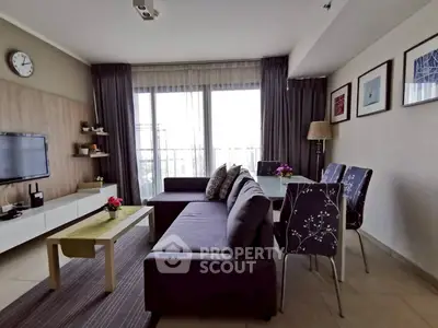 Modern living room with stylish decor, featuring a cozy sofa, wall-mounted TV, and elegant dining area.