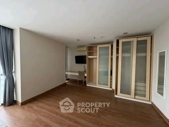 Spacious modern room with wooden flooring and built-in storage cabinets