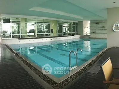 Luxurious indoor swimming pool with modern design and gym view, perfect for relaxation and fitness.