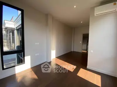 Spacious sunlit room with large window and modern air conditioning unit, perfect for a cozy living space.