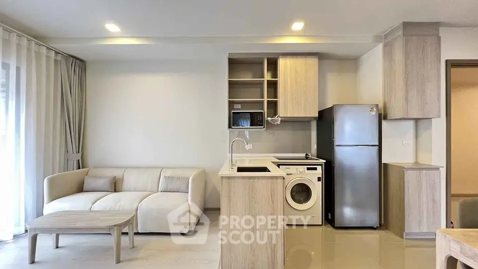 Modern open-plan living room with kitchen, featuring sleek appliances and cozy sofa.