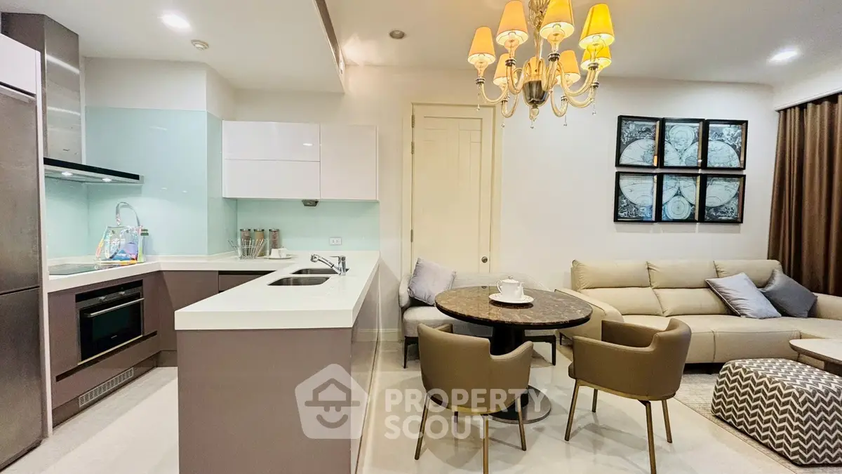 Modern open-layout kitchen and living room with elegant chandelier and cozy seating area.