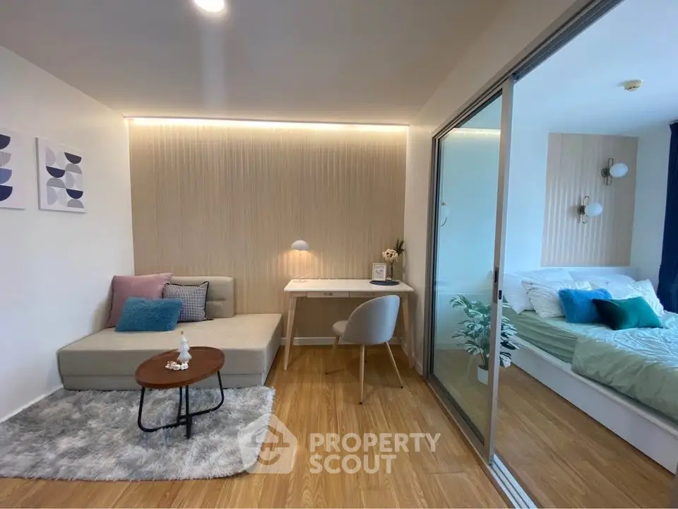Modern studio apartment with cozy living area and stylish bedroom separated by glass partition.