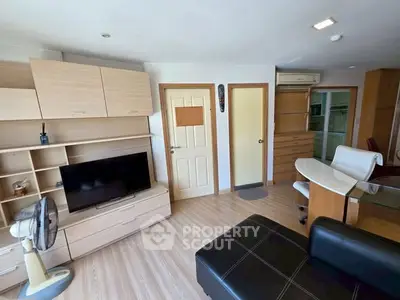 Modern living room with sleek furniture and TV, featuring light wood accents and ample storage space.