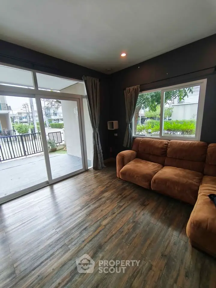 Spacious living room with large windows and cozy sofa, overlooking a lush garden.