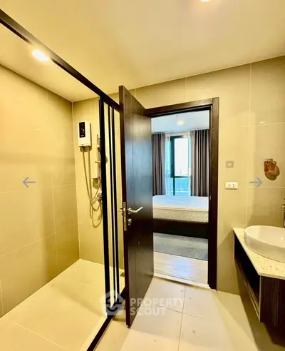 Modern bathroom with shower and view into a stylish bedroom