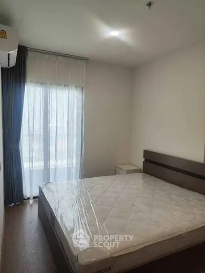 Modern bedroom with large window and natural light, featuring a neatly made bed and minimalist decor.