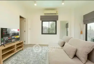 Modern living room with cozy sofa, TV, and natural light from window.