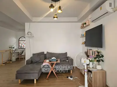 Cozy living room with modern decor, featuring a comfortable sofa, wall-mounted TV, and stylish lighting.