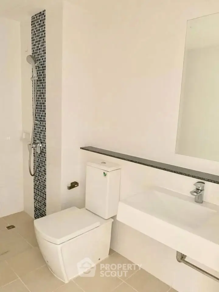 Modern bathroom with sleek fixtures and tiled shower area in a contemporary home.