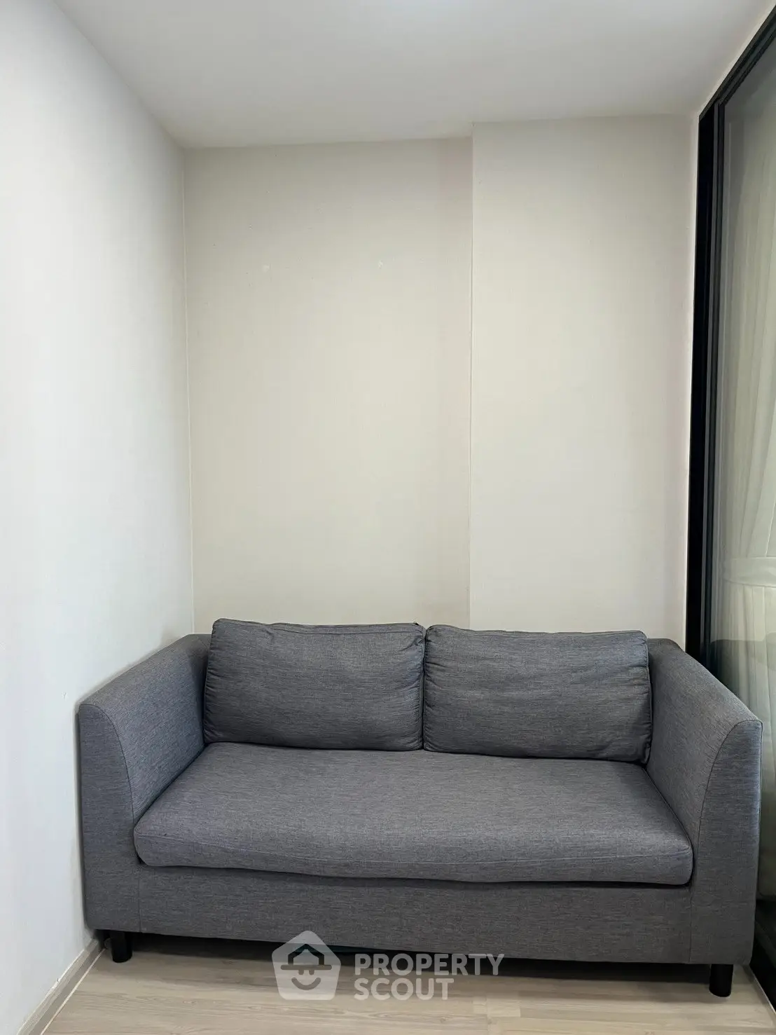 Modern minimalist living room with sleek gray sofa and large window
