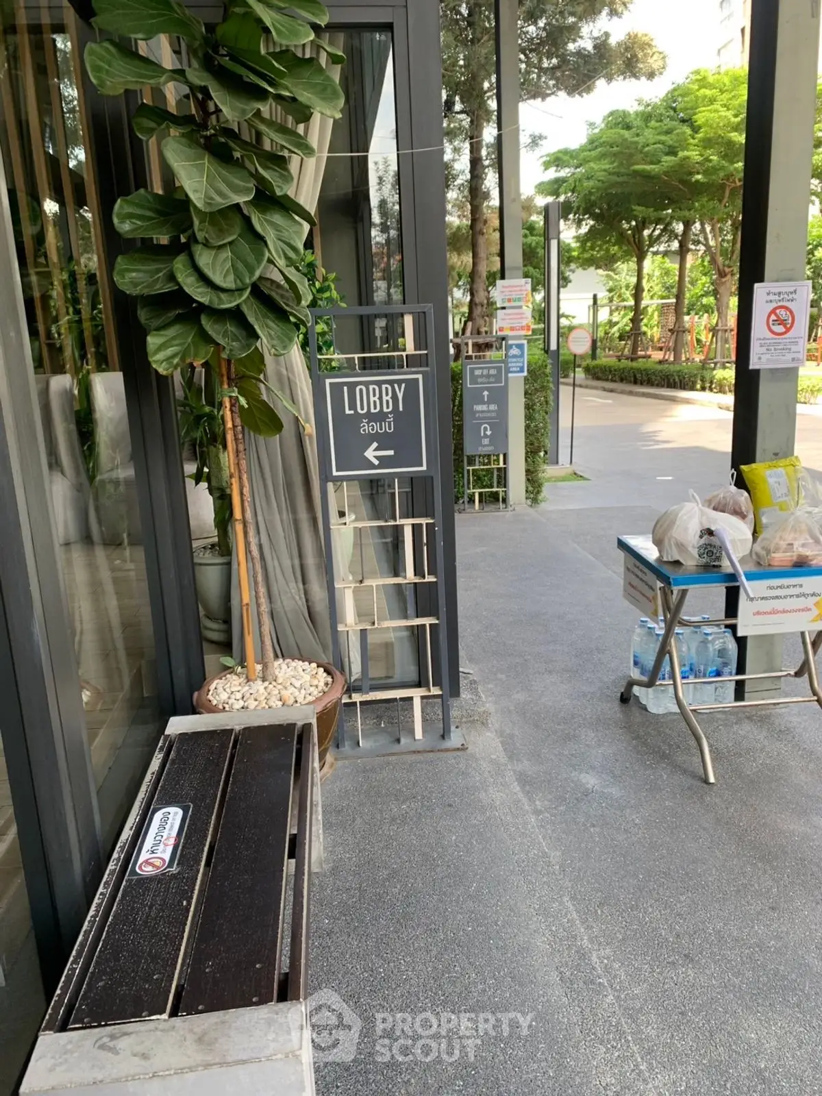Modern building entrance with lush greenery and lobby sign