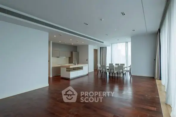 Spacious modern living room with open kitchen and dining area, featuring elegant hardwood floors.