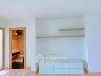 Minimalist living room with built-in shelves and view into modern bathroom
