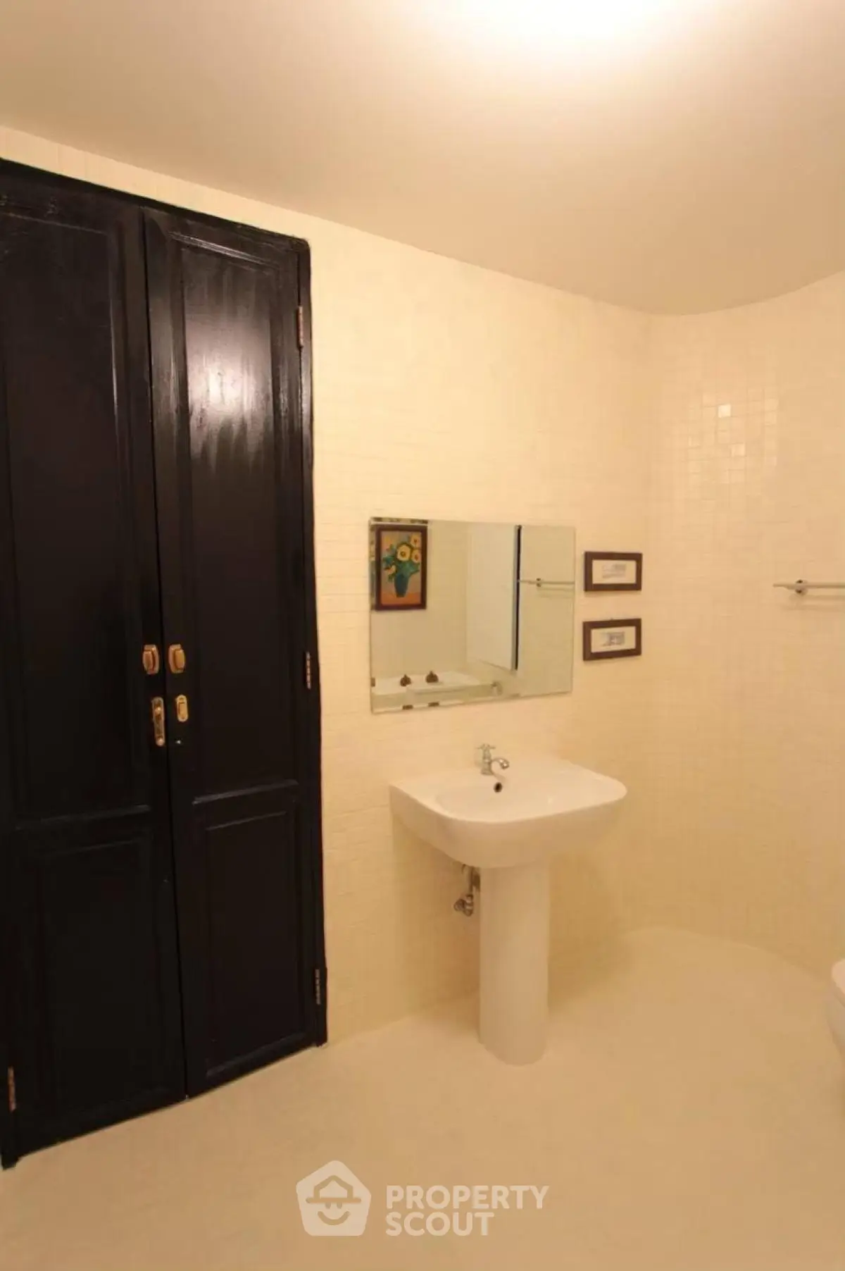Elegant bathroom with pedestal sink and dark wooden cabinet doors.
