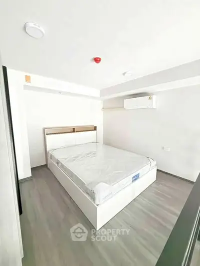 Modern minimalist bedroom with sleek flooring and air conditioning.