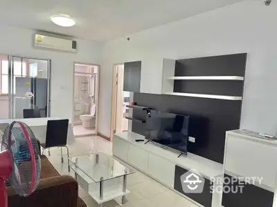 Modern living room with sleek furniture and open layout, featuring a TV and dining area.