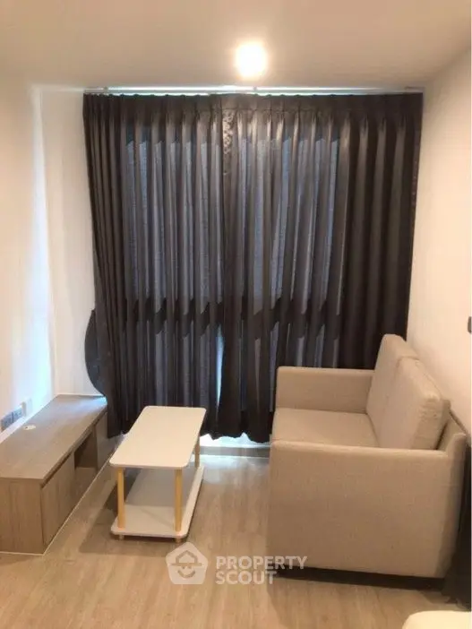 Cozy living room with modern sofa and stylish curtains in a compact space.