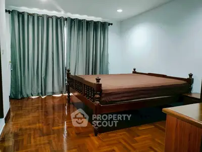 Spacious bedroom with elegant wooden bed and polished hardwood floors