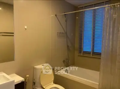 Modern bathroom with bathtub and window blinds in a cozy apartment.