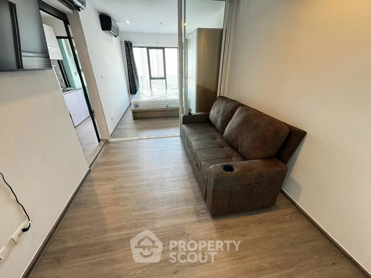 Modern apartment interior with cozy living room and bedroom view, featuring sleek wooden flooring and stylish furniture.