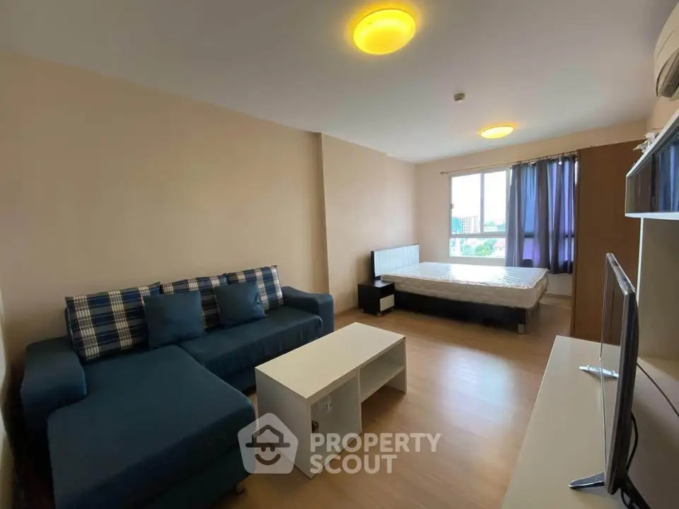 Spacious studio apartment with modern furnishings and large window view.