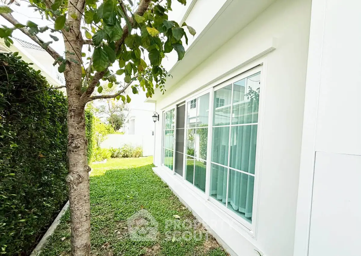 Charming garden view of modern home with large windows and lush greenery.