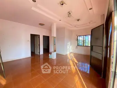 Spacious empty room with terracotta tiles and large windows offering natural light.