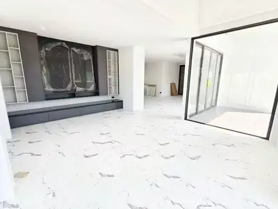 Spacious modern living room with marble flooring and large windows for natural light.