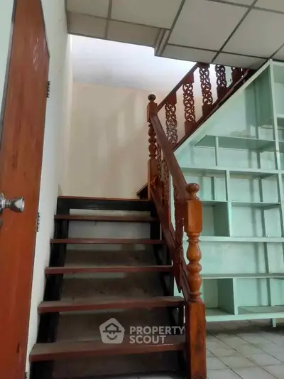 Charming staircase with wooden railing and built-in shelving in cozy home interior.