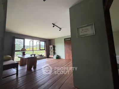 Spacious living room with wooden flooring and large windows offering scenic views.