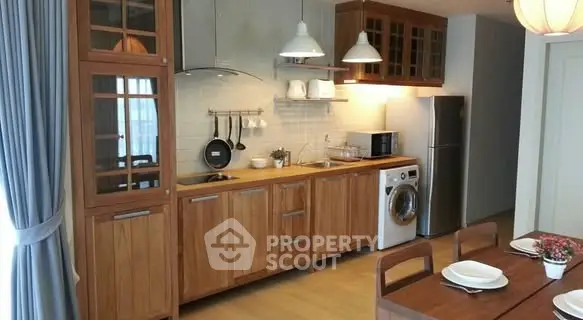 Modern kitchen with wooden cabinets, washing machine, and dining area