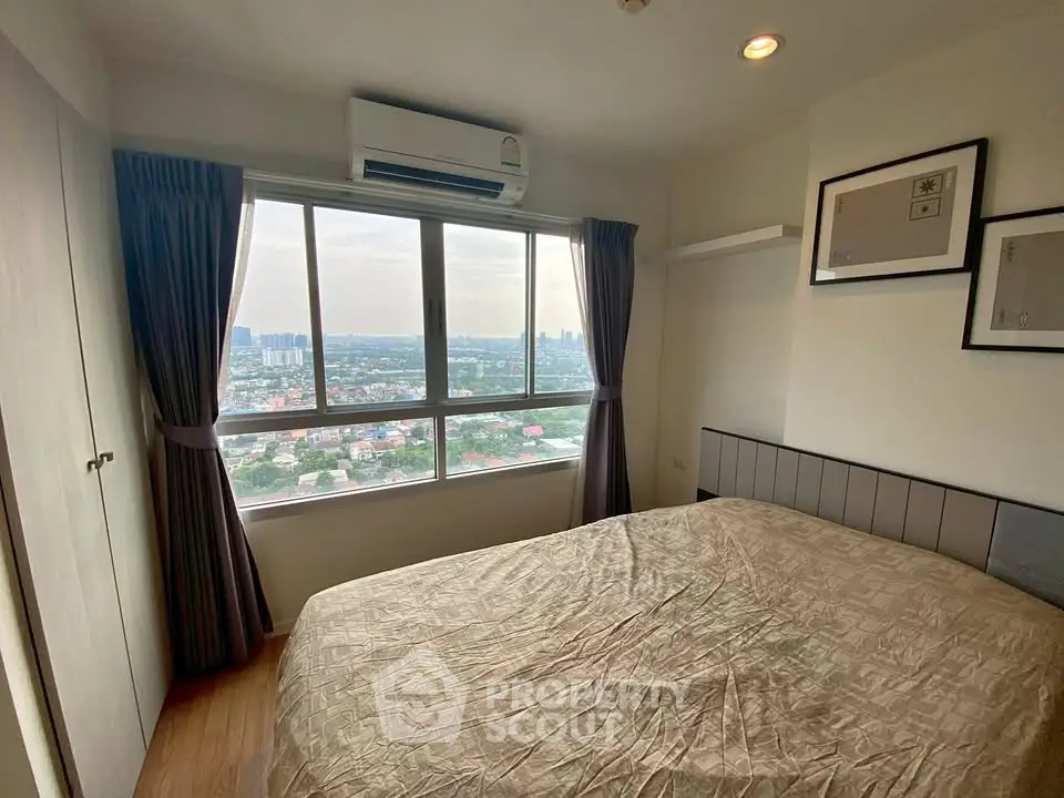 Cozy bedroom with large window offering stunning cityscape views, featuring modern decor and air conditioning.