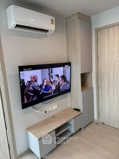 Modern living room with wall-mounted TV and air conditioning unit, featuring sleek storage solutions.