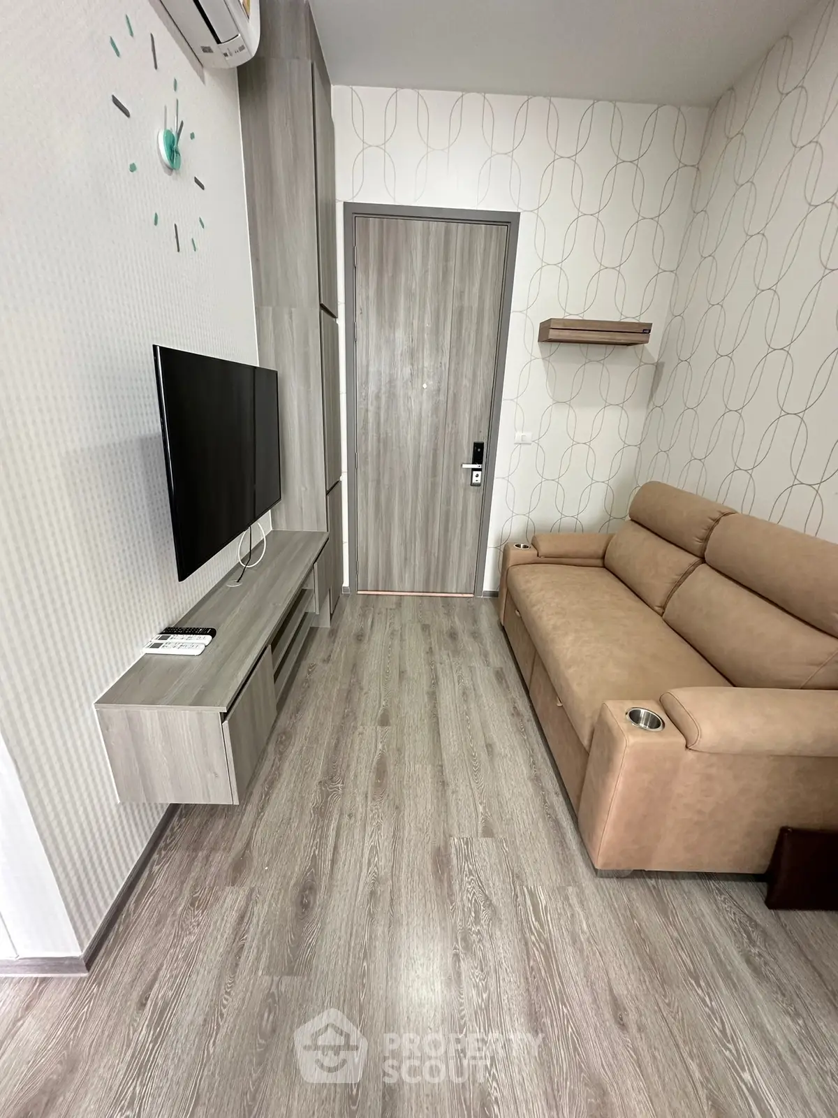 Modern living room with sleek design and cozy sofa, featuring wall-mounted TV and stylish flooring.