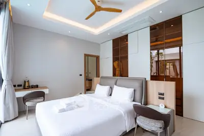 Luxurious modern bedroom with elegant design and ample natural light, featuring a stylish ceiling fan and cozy seating area.
