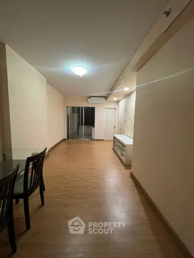 Spacious living room with wooden flooring and modern lighting in a stylish apartment.