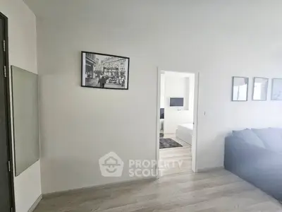 Modern apartment interior with cozy living room and bedroom view, featuring stylish decor and wooden flooring.